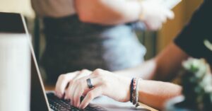 Close-up of hands typing on a laptop with a blurred background.